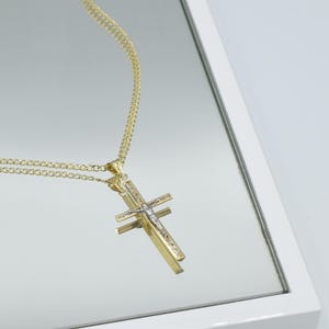 Puede incluir: Un collar de cadena de oro con un colgante de cruz de dos tonos. La cruz est&aacute; hecha de oro y plata y presenta una peque&ntilde;a figura de Jes&uacute;s.