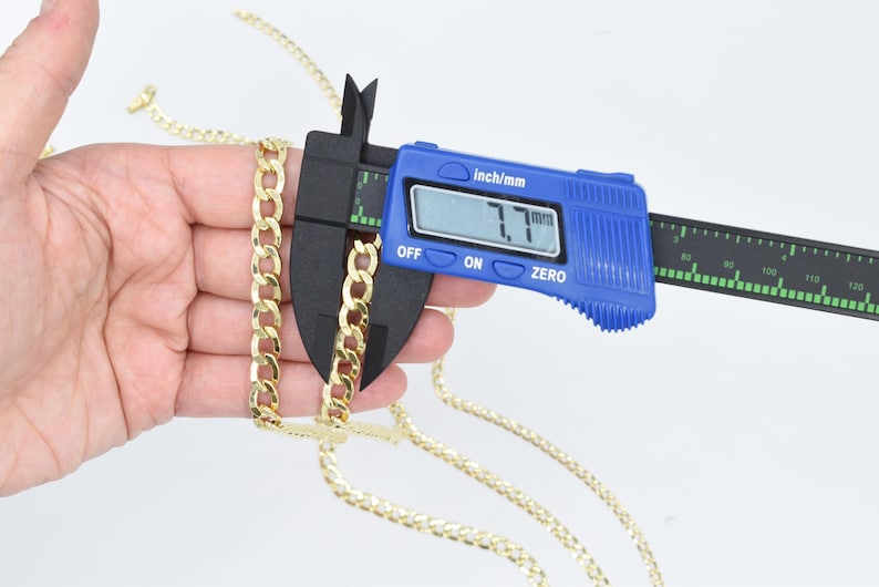 May include: A gold chain necklace is being measured with a blue digital caliper. The caliper reads 7.7 mm.