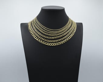 May include: A set of gold curb chain necklaces of varying widths displayed on a black velvet stand. The chains are arranged in order of size, with the smallest chain at the top and the largest chain at the bottom.