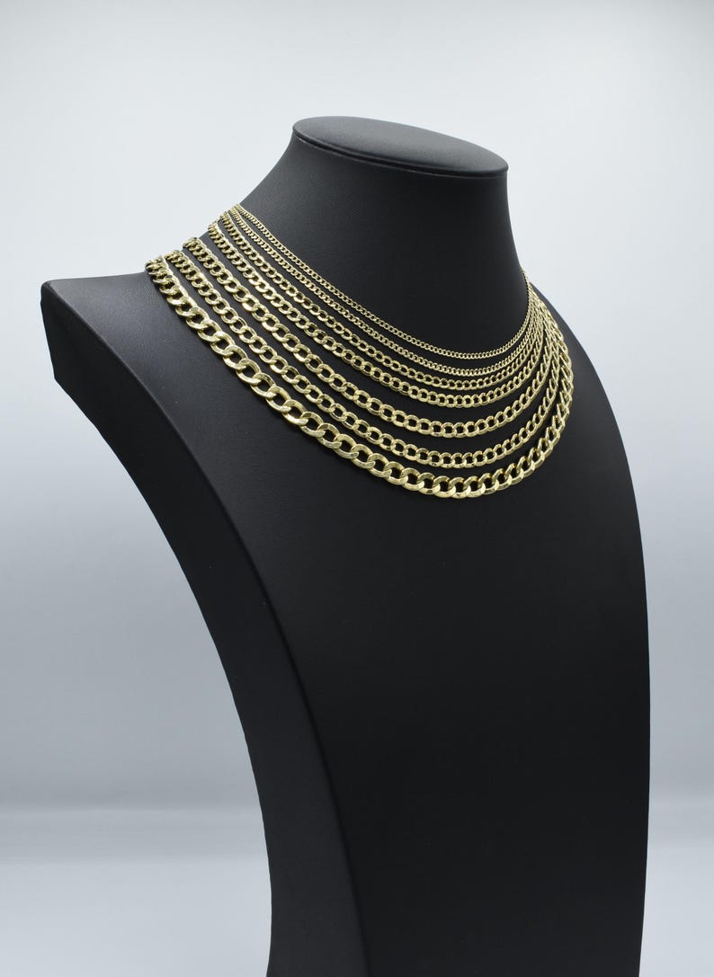 May include: A set of gold curb chains of varying widths displayed on a black mannequin bust. The chains are arranged in order of size, with the smallest chain at the top and the largest chain at the bottom.