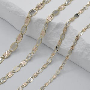 Puede incluir: Cuatro collares de oro con eslabones ovalados y en forma de estrella alternados. Los eslabones son una mezcla de oro amarillo, rosa y blanco. Los collares se exhiben sobre una superficie blanca texturizada.
