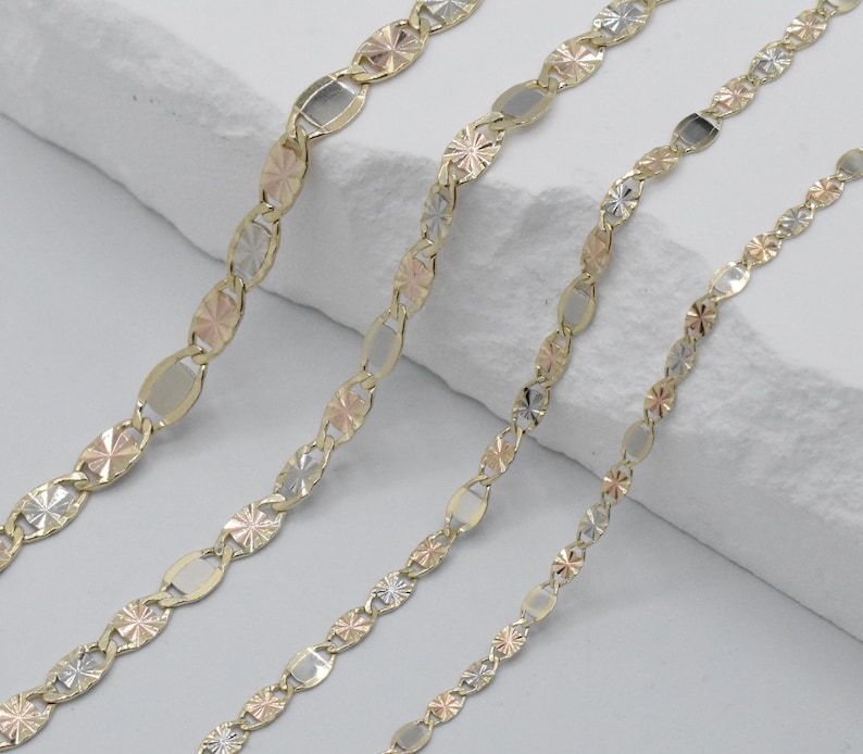 Puede incluir: Cuatro collares de oro con eslabones ovalados y en forma de estrella alternados. Los eslabones son una mezcla de oro amarillo, rosa y blanco. Los collares se exhiben sobre una superficie blanca texturizada.