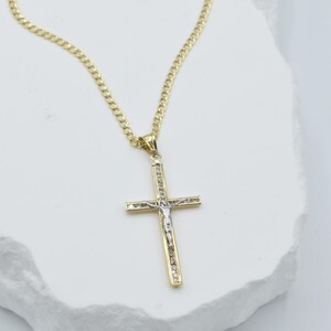 Puede incluir: Un collar de cadena de oro con un colgante de cruz de dos tonos. La cruz est&aacute; hecha de oro y plata y presenta un dise&ntilde;o detallado de una figura en la cruz.