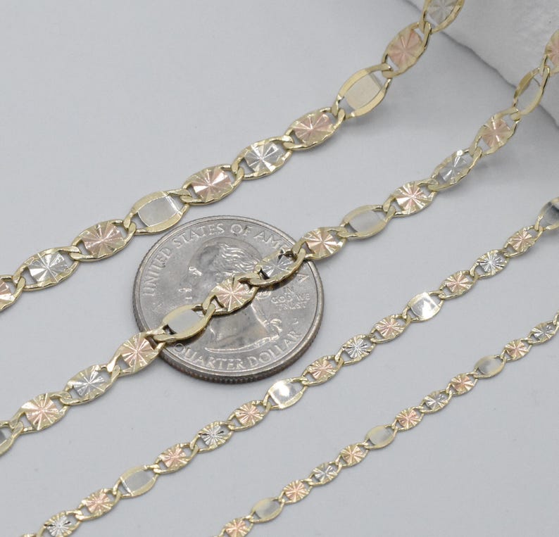 Puede incluir: Primer plano de tres cadenas de oro con una moneda de veinticinco centavos para comparar el tama&ntilde;o. Las cadenas presentan una mezcla de oro amarillo, rosa y blanco. Las cadenas tienen un patr&oacute;n repetitivo de eslabones ovalados y en forma de estrella.