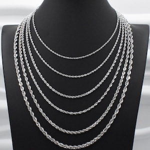 May include: A display of multiple silver rope chain necklaces of varying lengths. The necklaces are arranged on a black mannequin, showcasing the different sizes and styles. The chains have a twisted rope design, reflecting light.