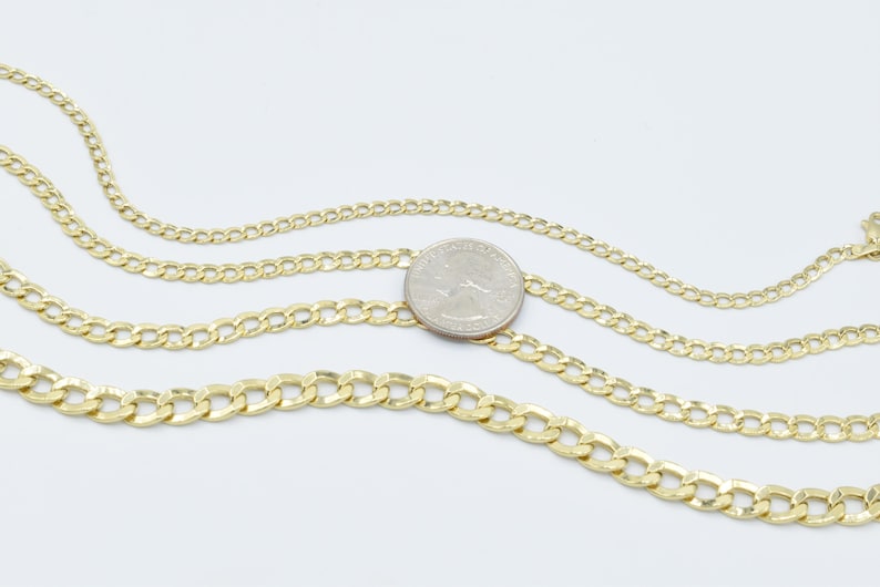 May include: Three gold chains of different thicknesses, laid out on a white surface. A US quarter is placed on top of the chains for size comparison.