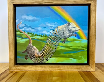 May include: A framed painting featuring a white opossum with a long, metallic, coiled spring body stretching across a green landscape under a blue sky with a rainbow. The artwork is encased in a light-toned wooden frame with a simple, clean edge.