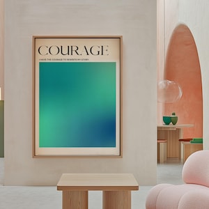 Op de afbeelding: Een ingelijst drukwerk met een groene en blauwe gradiënt achtergrond. De tekst "COURAGE" is in het zwart bovenaan het drukwerk gedrukt. Onder de tekst staat de zin "IK HEB DE MOED OM MIJN VERHAAL TE HER-SCHRIJVEN."