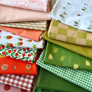 May include: A collection of folded fabric pieces in various patterns and colors. Includes fabrics with strawberries, flowers, gingham, and polka dots. Colors range from pinks and oranges to greens and white. Some fabrics have repeating patterns.