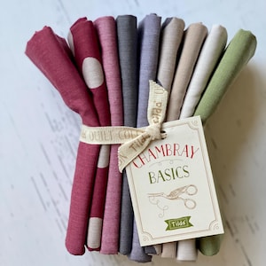 May include: A stack of 10 fabric squares in various colors, including red, pink, gray, beige, and green. The fabric squares are tied together with a white ribbon and a tag that reads " Chambray Basics Tilda".