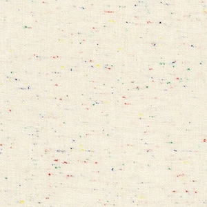 May include: A close-up of a white fabric with a speckled pattern of red, blue, green, and yellow threads.