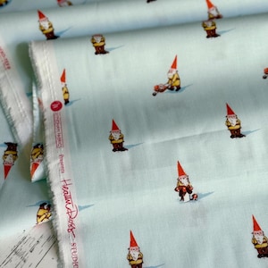 Puede incluir: Tela azul claro con un estampado repetido de gnomos de jardín con sombreros rojos y chaquetas amarillas. Los gnomos están en varias poses. La tela tiene el texto "Heather Ross Studio Edit".