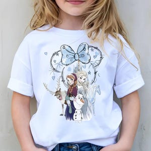 A young girl wearing a white t-shirt with a graphic of characters from the Disney movie Frozen.
