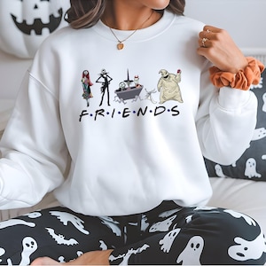 A person wearing a white sweatshirt with a graphic of characters from the TV show Friends, including Jack Skellington, Mary Jane, and the character Oogie Boogie, along with the text "FRIENDS".