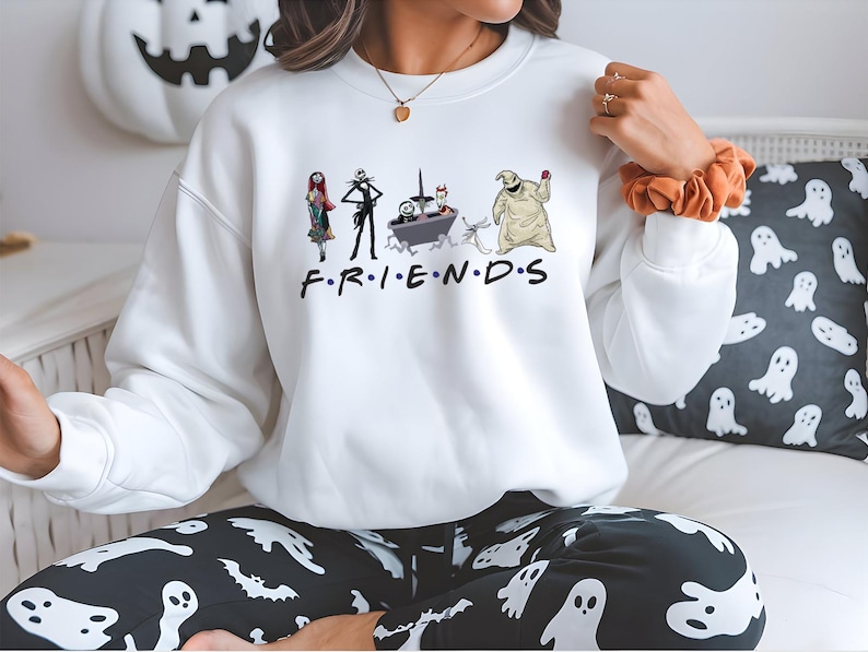 A person wearing a white sweatshirt with a graphic of characters from the TV show Friends, including Jack Skellington, Mary Jane, and the character Oogie Boogie, along with the text "FRIENDS".