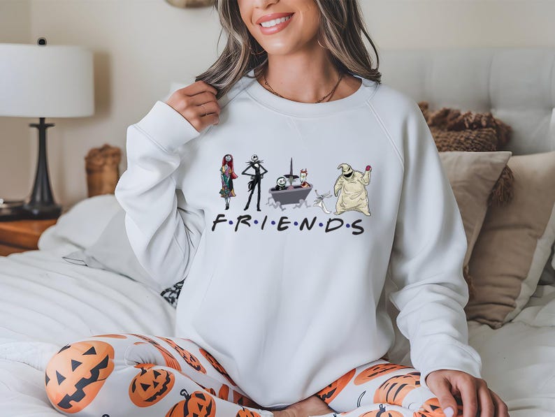 A woman wearing a white sweatshirt with a graphic design featuring characters from the TV show Friends.