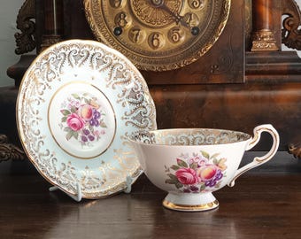 Preciosa y rara taza de té/platillo vintage Paragon Royal Ward de porcelana fina inglesa con borde ancho dorado, diseño de rosas rosadas y frutas, década de 1950, en excelente estado.