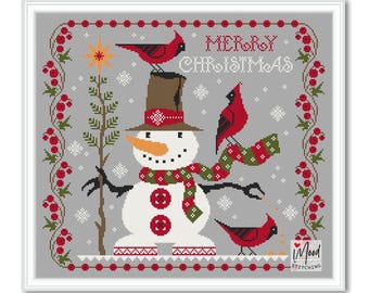 Könnte beinhalten: Ein Kreuzstich-Design mit einem Schneemann mit braunem Hut und Schal, auf dem rote Kardinäle sitzen. Die Worte „MERRY CHRISTMAS“ stehen oben, umgeben von einem Rand aus roten Beeren und grünen Blättern. Das Design ist gerahmt.