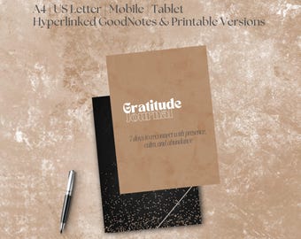 May include: A gratitude journal with a tan cover and the title "Gratitude Journal" in white script. The journal is stacked on top of a black journal with white speckles. A silver pen rests on the surface.