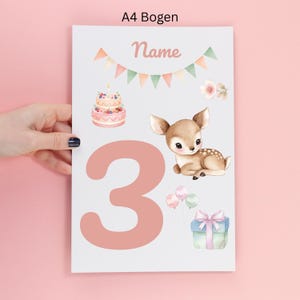 Könnte beinhalten: Ein A4-Bogen mit einer großen rosa Zahl 3, einem braunen Rehkitz, einer zweistöckigen Geburtstagstorte, einem Geschenk mit rosa Schleife, drei Luftballons, einer Blüte und einer Wimpelkette. Der Text "Name" steht oben auf dem weißen Papierbogen.