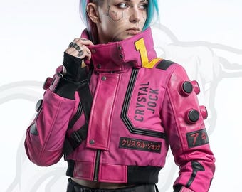 May include: A cropped pink leather jacket featuring a high collar with a yellow number one, black accents, and the text CRYSTAL JOCK printed on the chest. The jacket includes circular black buttons on the sleeves and Japanese text on the arm.