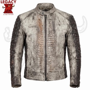 May include: A jacket with a textured crocodile skin pattern in shades of off-white, grey, and dark brown. The garment features a central zipper, a mandarin collar with a snap button, and long sleeves. The Legacy Leather logo is in the top left corner.