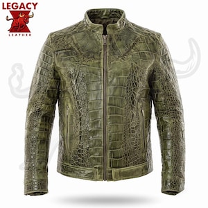 Puede incluir: Una chaqueta de color verde oliva con un patrón texturizado de piel de cocodrilo, que presenta un cuello alzado, una cremallera central de metal y dos bolsillos laterales con cierre de cremallera. El texto LEGACY LEATHER aparece arriba a la izquierda.