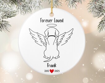 May include: A white ceramic Christmas ornament with a gold string for hanging. The ornament features a black line drawing of a dog with angel wings and a halo. Text includes "forever loved", the name "Frank", and dates 2012-2025 with a red heart.