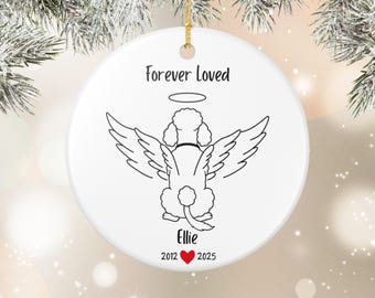 May include: A white ceramic ornament with a gold string for hanging. The ornament features a black line drawing of a poodle with angel wings and a halo. Text reads "Forever Loved," the name "Ellie," and dates 2012-2025 with a red heart.