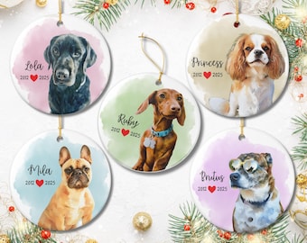 May include: Round ceramic ornaments featuring watercolor portraits of dogs. Each ornament has a different dog breed, with the dog's name and dates printed below. The ornaments are decorated with gold hanging strings and festive greenery.