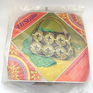 May include: A HiStraw Puerto Vallarta Handbag kit in a clear plastic package. The kit includes a brown and tan handbag with circular woven accents, a green scarf, and sunglasses. The packaging features colorful geometric designs and text.