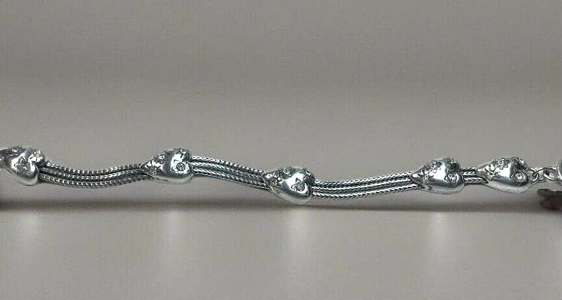 Peut inclure: Un bracelet en argent avec un design de cha&icirc;ne et des breloques en forme de c&oelig;ur. Chaque breloque en forme de c&oelig;ur a de petites pierres claires.