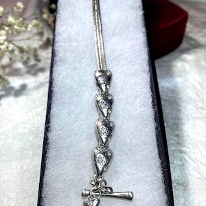 Peut inclure: Un bracelet en argent avec un motif de charme en forme de c&oelig;ur. Le bracelet a un fermoir &agrave; bascule et est compos&eacute; de plusieurs brins de cha&icirc;ne.