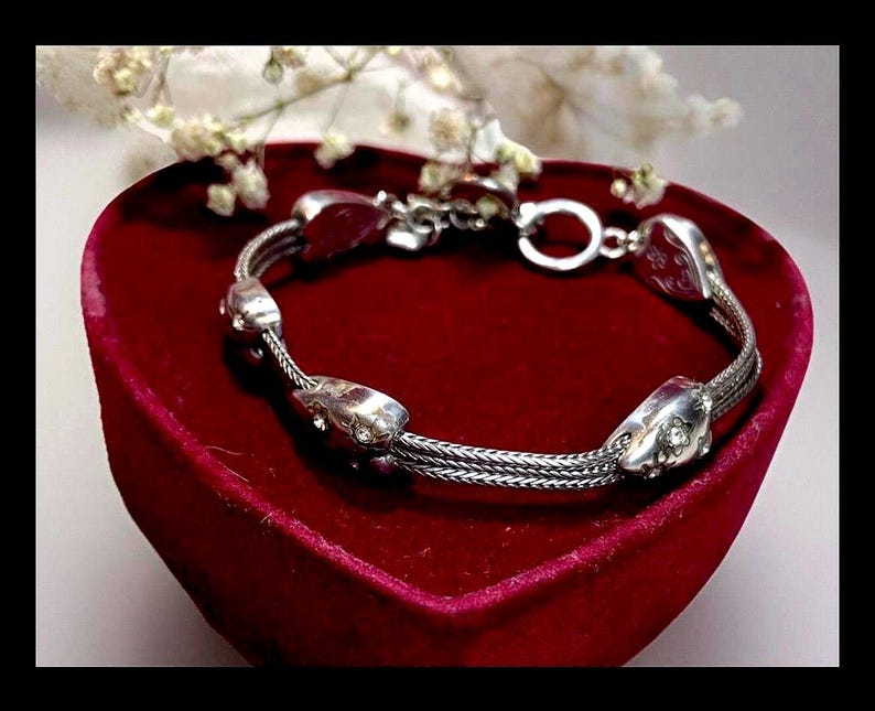 Peut inclure: Un bracelet en argent avec une cha&icirc;ne tress&eacute;e et des breloques en forme de c&oelig;ur. Le bracelet est pr&eacute;sent&eacute; dans un &eacute;crin en velours rouge en forme de c&oelig;ur.