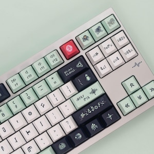 May include: A custom mechanical keyboard with a light grey case and a variety of keycap colours, including white, black, mint green, and red. The keycaps feature unique symbols and text, with a minimalist design.
