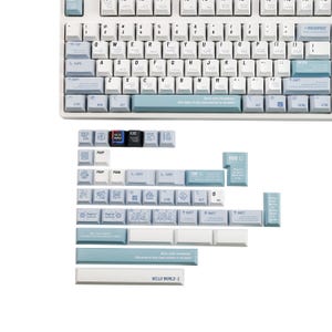 May include: A white mechanical keyboard with light blue accents and keycaps. The keyboard has a standard layout with alphanumeric keys, function keys, and a number pad. Additional keycaps are included, some with text like "HELLO WORLD :)" and "404".