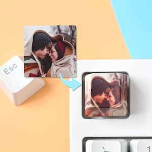 May include: A white computer keyboard with a close-up of a custom keycap featuring a photo of a couple. The keycap is square and shows a couple smiling and embracing. The Esc key is also visible.