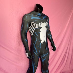 May include: Black and blue superhero costume with a white spider emblem on the chest. The full-body suit features blue streaks and white accents. The costume is displayed on a mannequin.