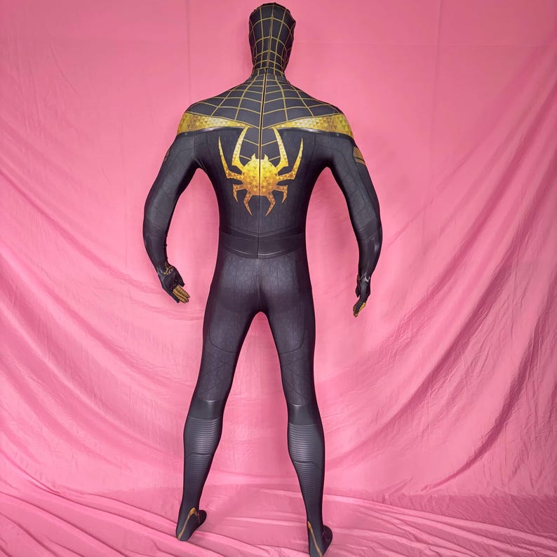 以下が含まれることがあります： 黒と金の スパイダーマンのコスチューム。全身スーツは、肩、スパイダーエンブレム、ウェブデザインに金のアクセントが付いた黒いベースが特徴です。コスチュームにはフードと手袋が含まれています。