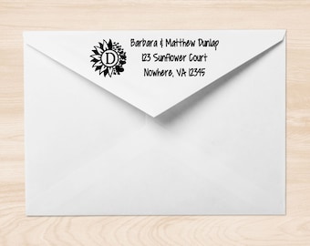 May include: A white envelope with a black return address label. The label features a sunflower graphic with a black circle containing the letter "D" in the center. The text on the label reads "Barbara & Matthew Dunlap, 123 Sunflower Court, Nowhere, VA 12345."