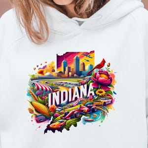 May include: White hooded sweatshirt with a colorful graphic design of the state of Indiana. The design features a cityscape, race cars, corn, sunflowers, and a cardinal.