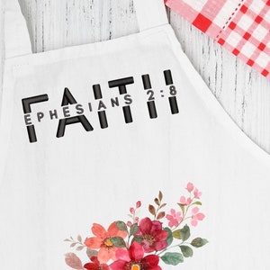 May include: White apron with the text "FAITH EPHESIANS 2:8" and a floral design. Add Flowers to accentuate their Apron Great gift for Mom, Sister, GrandMa or Sister-in-law