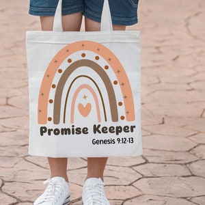 Puede incluir: Una bolsa de tela blanca con un gráfico de arcoíris en tonos melocotón, bronceado y marrón. El diseño incluye pequeños detalles de estrellas y puntos, un corazón central y el texto Promise Keeper con Genesis 9:12-13 debajo.
