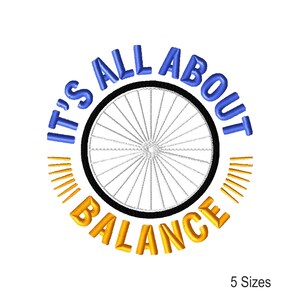 May include: Embroidered design with a bicycle wheel and the text "IT'S ALL ABOUT BALANCE" in blue and gold. Gold radiating lines surround the wheel. The text "5 Sizes" is at the bottom right of the design.