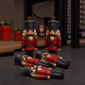 May include: Miniature nutcracker figurines in a festive arrangement. Two stand upright, and four are lying down. The nutcrackers feature red jackets, blue hats, and white beards. Gold detailing is present. The background is dark, with hints of Christmas decor.