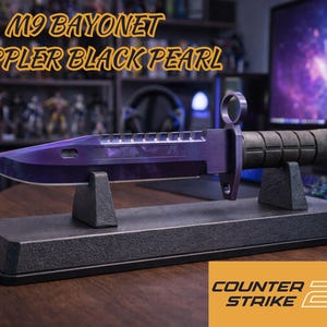 Pode incluir: Uma faca M9 Bayonet Doppler Black Pearl, exibida em um suporte preto. A lâmina tem um gradiente roxo e preto. A alça é verde escuro e preta. O texto "M9 BAYONET DOPPLER BLACK PEARL" está acima da faca.