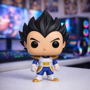 Può includere: Una statuetta in vinile di Vegeta di Dragon Ball Z. La statuetta ha capelli neri a spillo, un viso abbronzato e indossa un completo blu e bianco con dettagli dorati. La statuetta è in piedi su una superficie bianca.