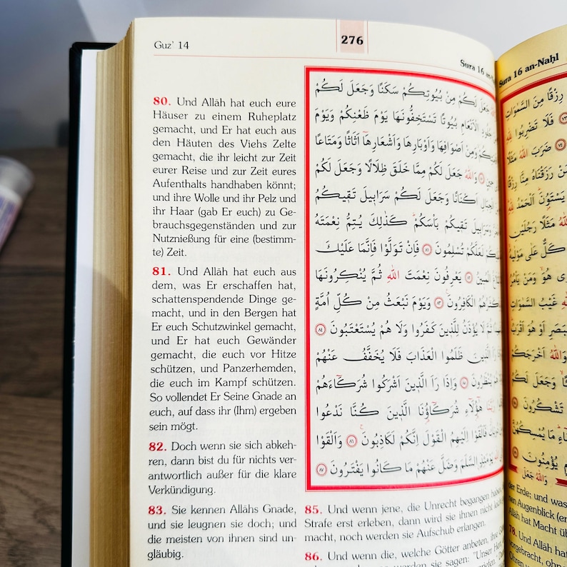 May include: Open book with Arabic text on the right page and German text on the left. The book is open to pages 276 and 14, with the title "Sura 16 an-Nahl" visible.