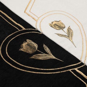 May include: Close-up of a black and white textile with gold floral designs. The design features a tulip in an oval frame, with gold lines and accents. The background is split diagonally, with black on the bottom left and white on the top right.