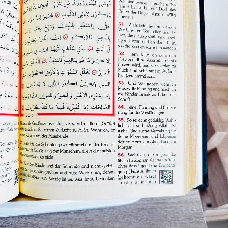 May include: Open book with Arabic text and German translation. The pages are yellowed, and the text is in black. The book is open to a page with a red border. The text is in both Arabic and German.